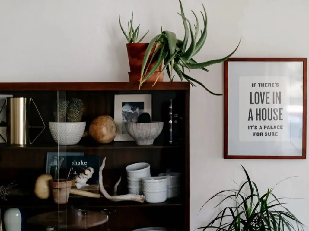 maison moderne familiale boheme retro salle à manger séjour vitrine rangement meuble foncé contraste mur blanc affiche à encadrer message amour