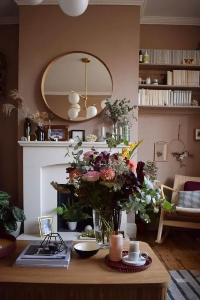 salon hiver cocooning exemple rose pastel cheminée blanche miroir rond bouquet de fleurs fauteuil vintage en bois
