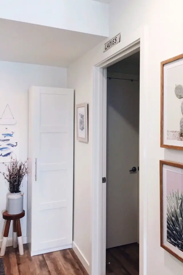 visite deco appartement studio cosy et doux porte de salle de bain couloir déco murale cadre petit tabouret vase fleur séchées