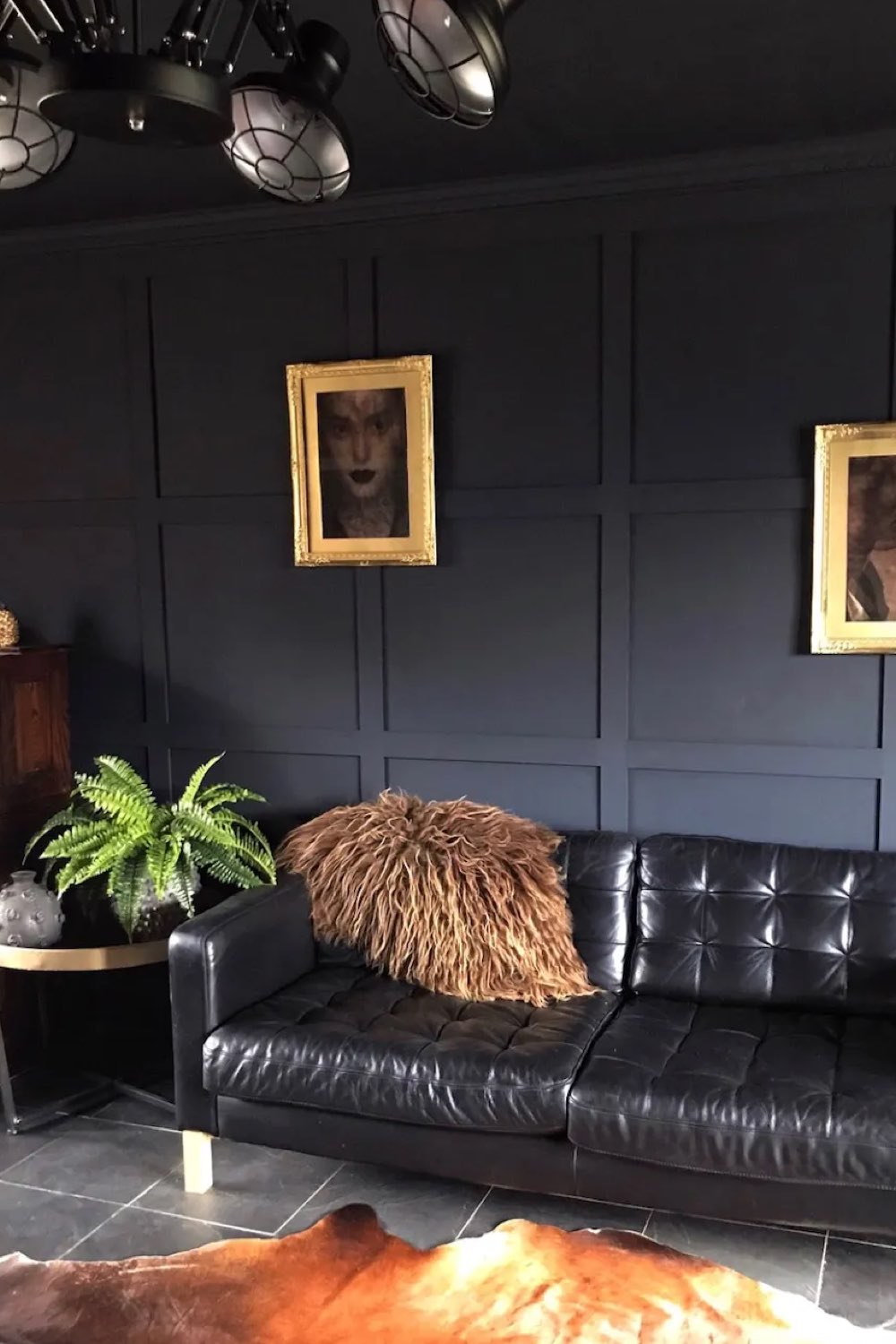 interieur couleur sourde eclectique salon peinture murale noire mat canapé cuir lumineux cadres dorés