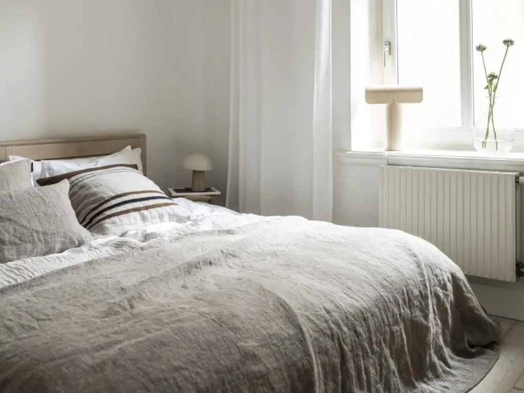 visite deco maison minimaliste cosy chambre à coucher reposante élégante épurée textiles naturels neutres parure de lit lumière naturelle