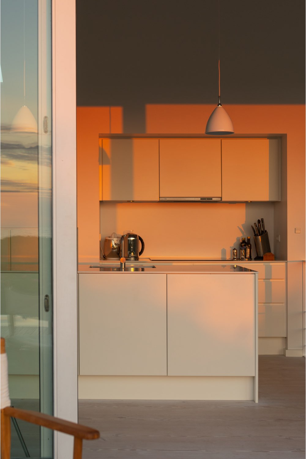 maison cotiere ultramoderne deco epuree cuisine éclairage naturel chaleureux coucher de soleil ambiance chaude apaisante relaxante