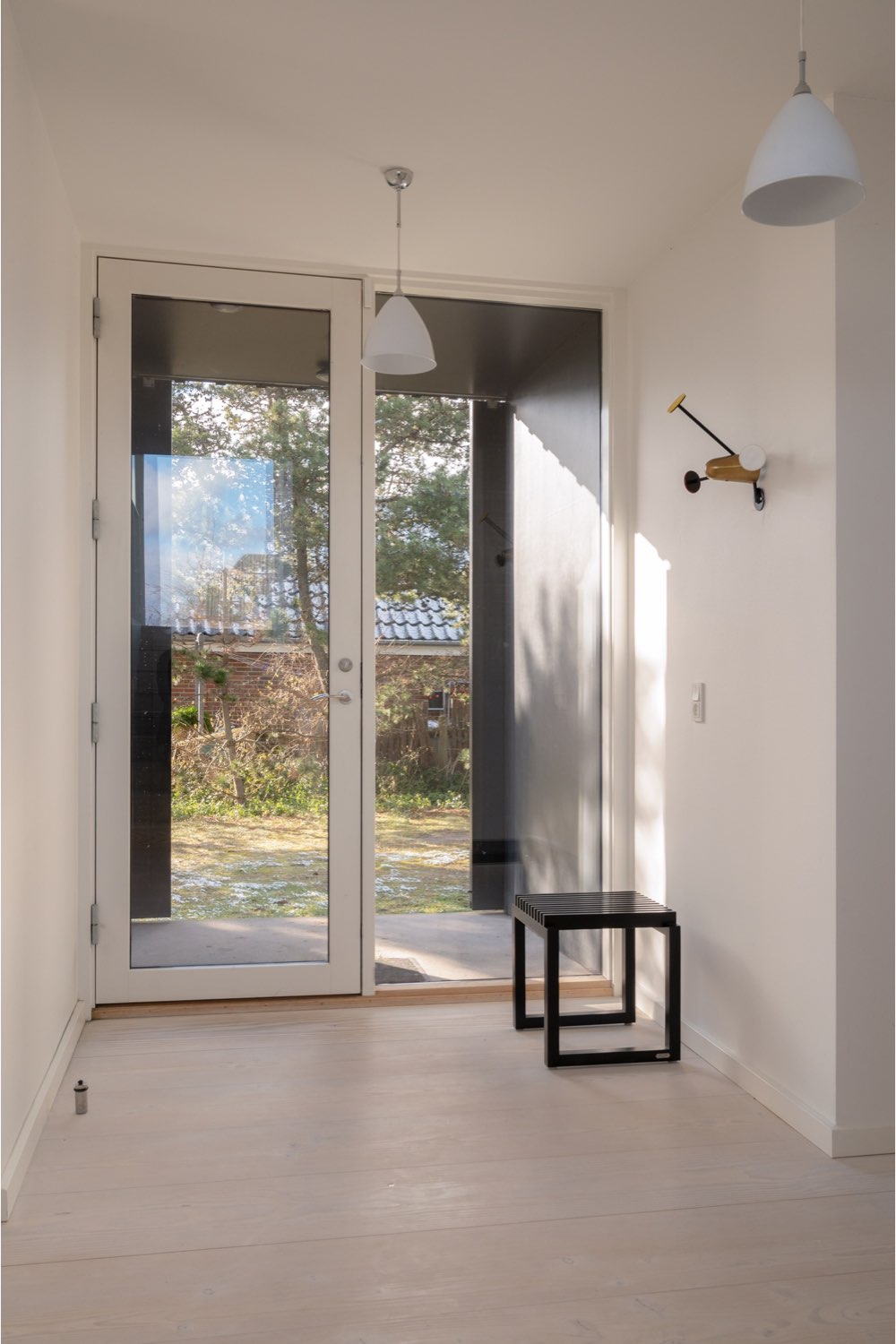 maison cotiere ultramoderne deco epuree détail entrée couloir minimaliste suspension blanche éclairage porte d'entrée vitrée