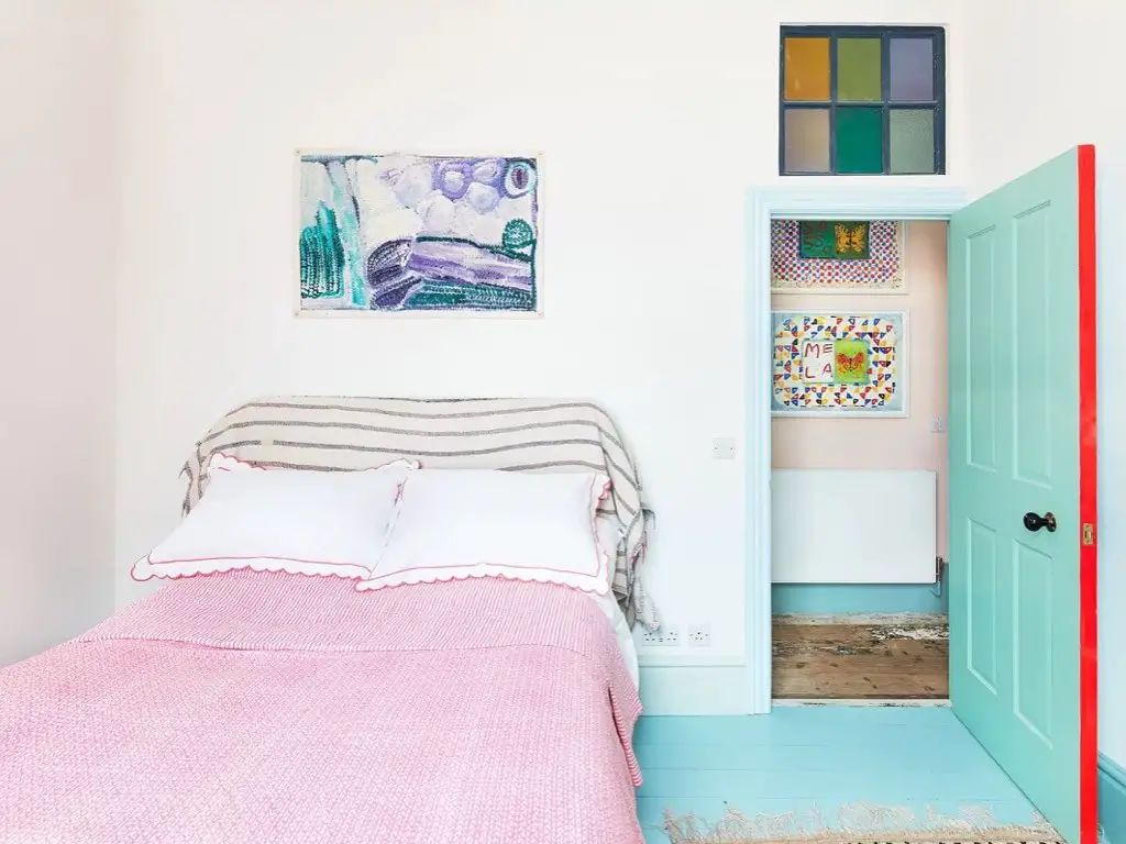 maison couleur pastel douce eclectique chambre d'ami blanche menuiserie porte peinte bleu avec arrête en rouge original parure de lit rose