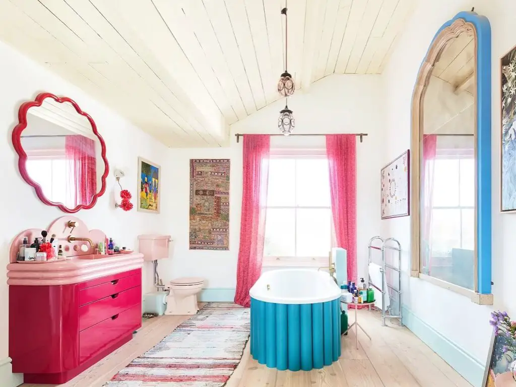 maison couleur pastel douce eclectique salle de bain principale habillage de baignoire original incurvé meuble rose 