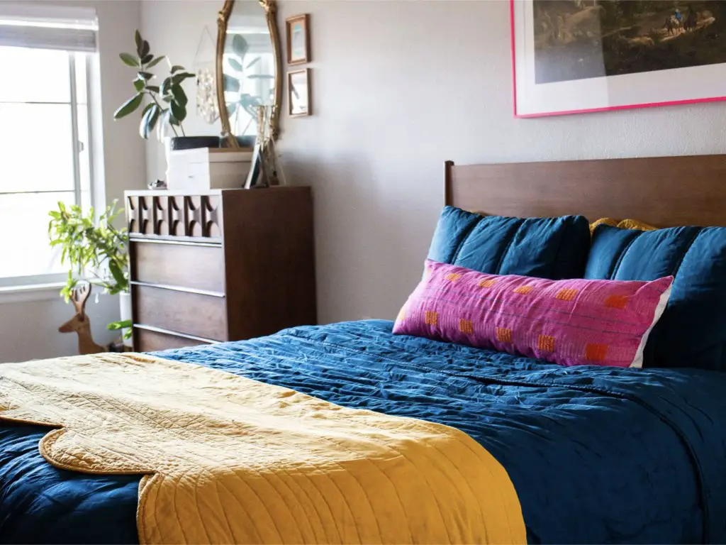 visite appartement decoration personnelle chambre à coucher simple adulte linge de lit coloré bleu jaune rose mobilier sombre en bois