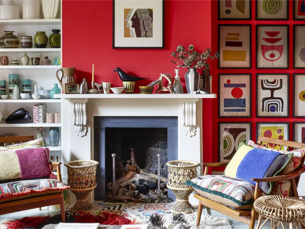 decoration maison style anglais ecelctique salon peinture rouge cheminée ancienne blanche galerie de cadre étagère collection vaisselle fauteuil housse de coussin fait maison