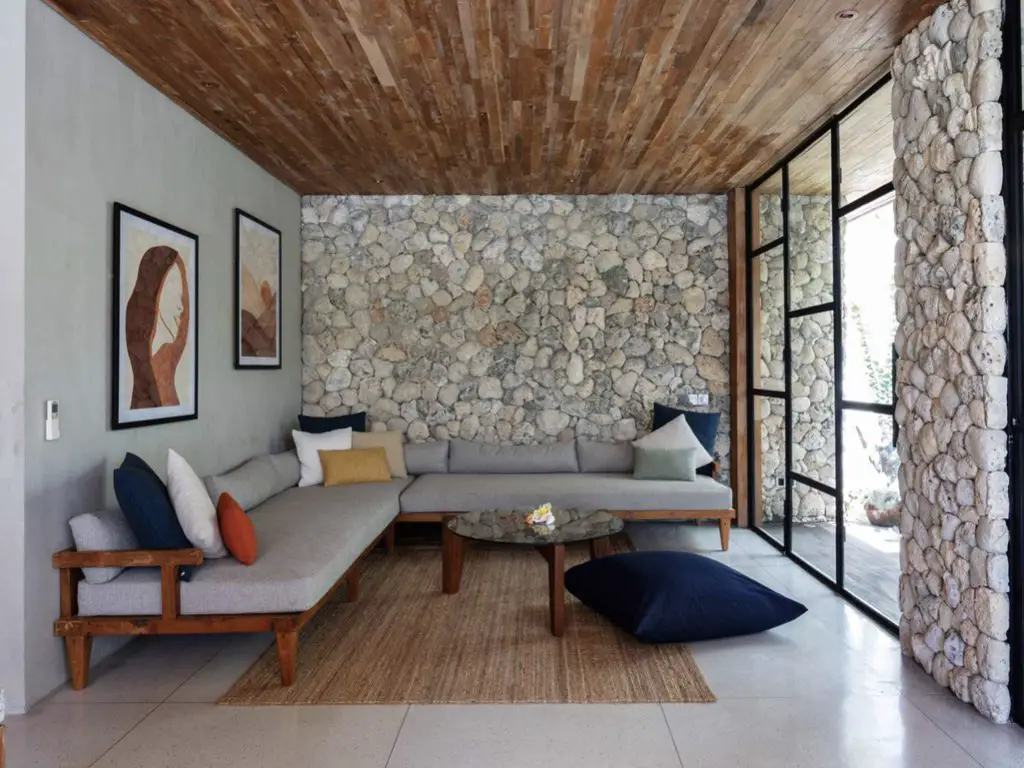 maison ouverte sur exterieur nature salon moderne avec grand canapé d'angle gris absence de télévision