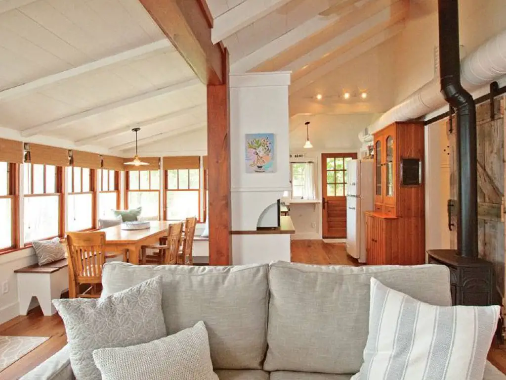 renovation chalet bord de lac grand salon séjour avec de nombreuses fenêtre poutres en bois mobilier couleur écru simple