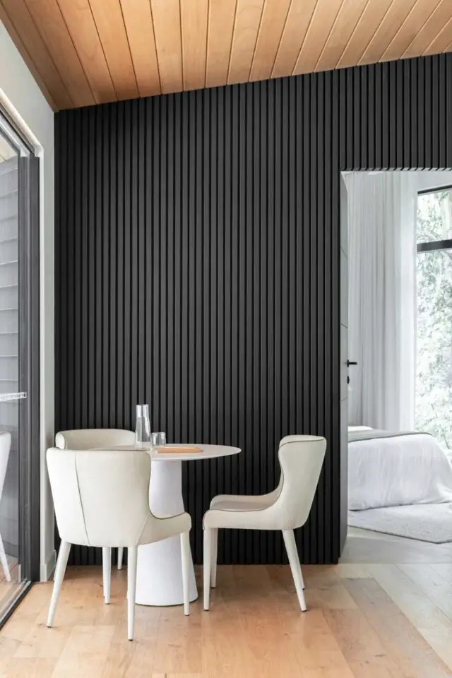 architecture interieure lodge mid century modern minimalisme coin repas maison invité mur en tasseaux noirs plafond en bois mobilier blanc et écru