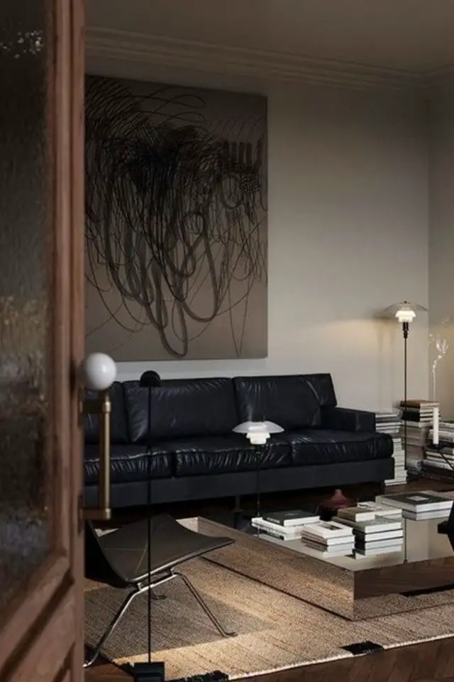 decoration masculine et slow living exemple salon séjour peu lumière naturelle canapé noir en cuir peinture murale beige écru tableau XXL abstrait luminaires design 