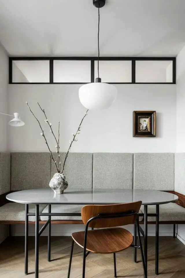 decoration masculine et slow living exemple verrière moderne en haut d'un mur intérieur lumineux blanc banquette grise salle à manger table ovale en marbre blanc