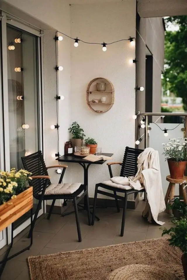 deco petit balcon petite table carrée avec deux fauteuil noir guirlande lumineuse et tapis