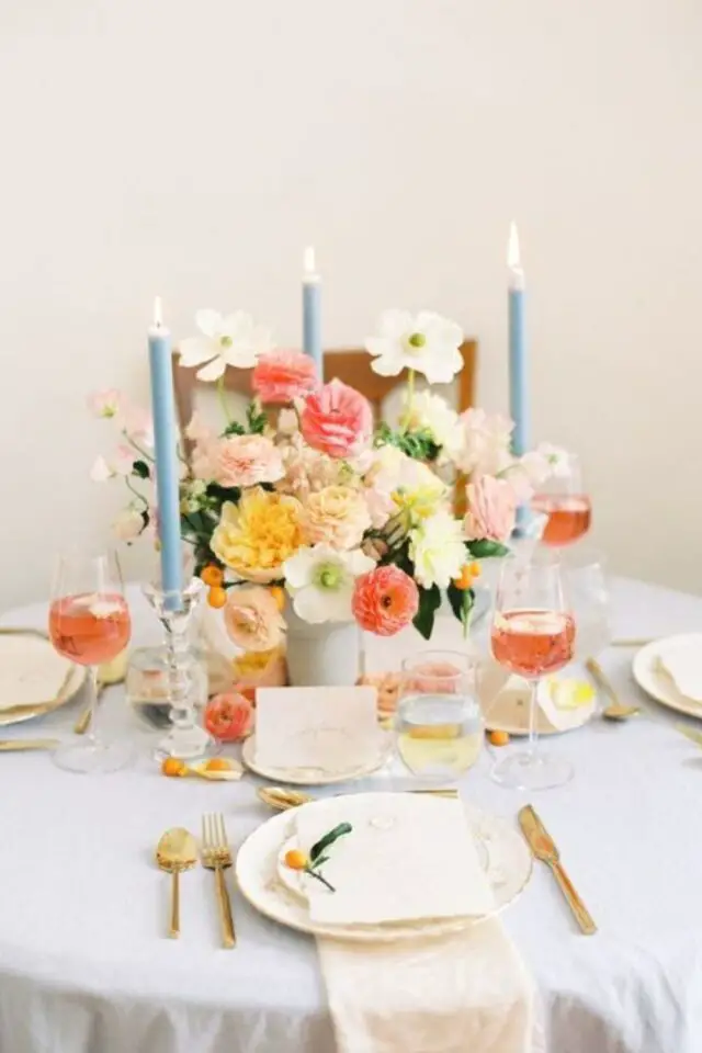 idee deco table fete pastel baptêle table ronde bouquet joyeux et coloré rose orange pêche blanc bougies bleues 