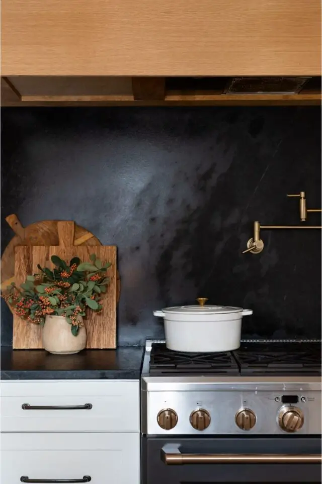Détail décor de cuisine plan de travail noir crédence peinture décorative noire brillante piano de cuisson habillage hotte en bois