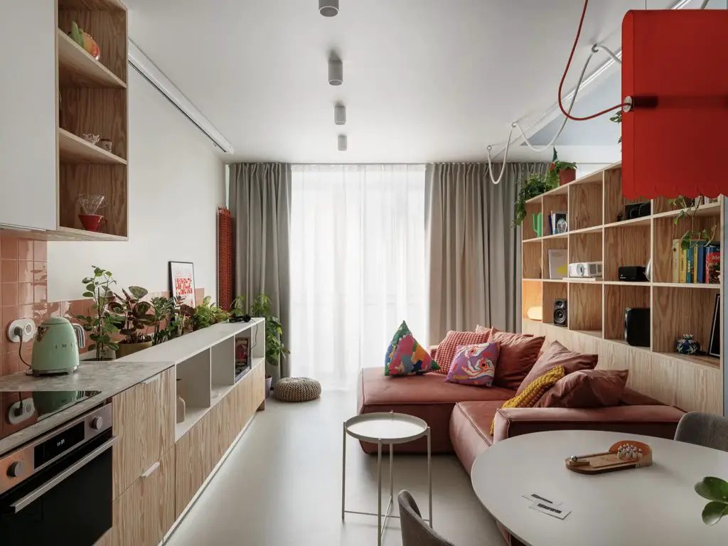 visite appartement 38m2 décor néo-rétro pièce à vivre en longueur coin repas table ronde canapé rose d'angle bibliothèque en bois cuisine en linéaire ouverte visite appartement 38m2 décor néo-rétro pièce à vivre en longueur coin repas table ronde canapé rose d'angle bibliothèque en bois cuisine en linéaire ouverte