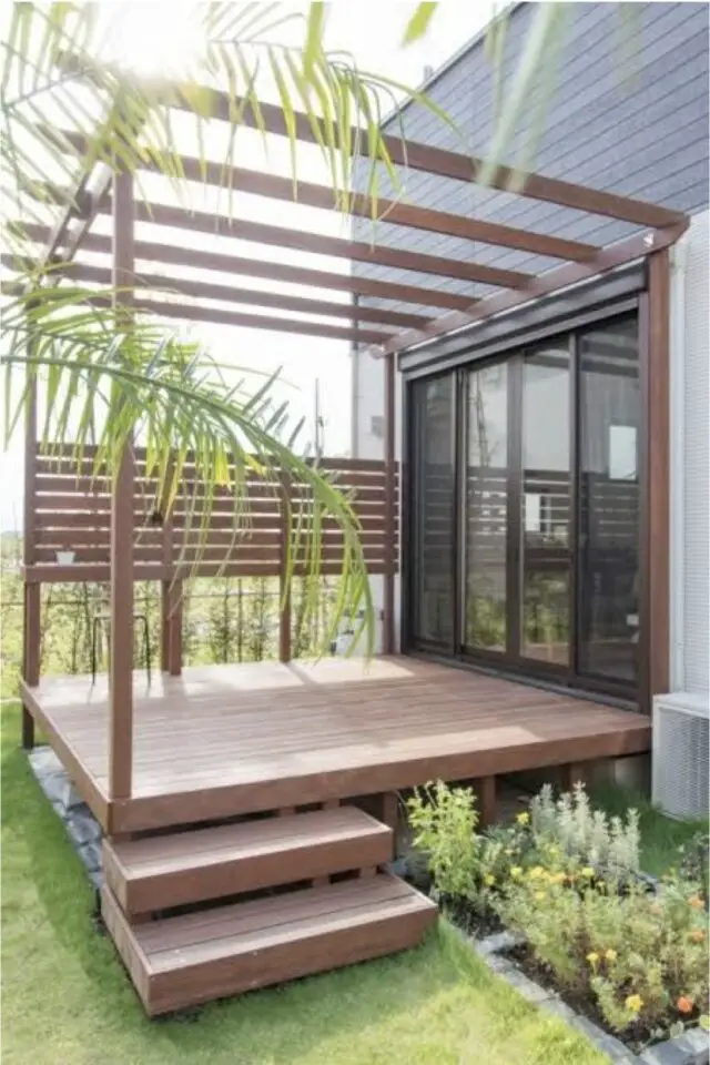 terrasse moderne en bois devant porte vitrée coulissante petite sur-élévation par rapport au jardin structure de pergola construction 