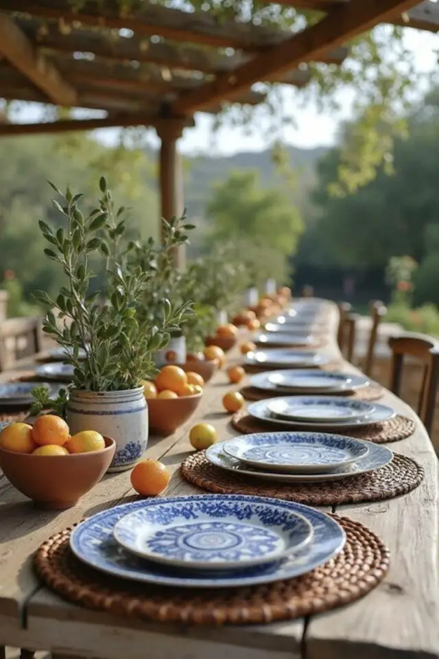 déco de table méditerranéenne exemple en extérieur grande table familiale set de table en fibre tressées assiettes bleues et blanches bol en terre cuite avec citron branche d'olivier 