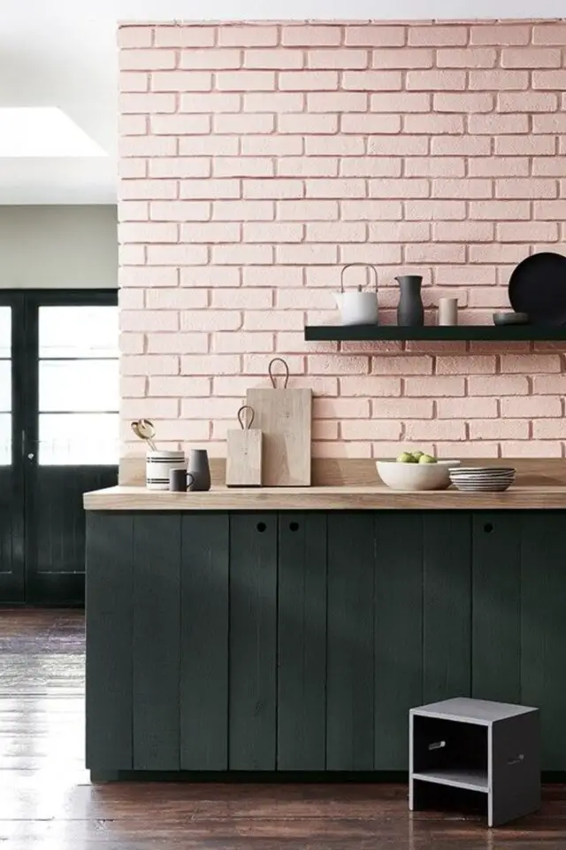 peindre un mur en brique exemple cuisine moderne contraste mur rose meuble noir plan de travail en bois clair ambiance minimaliste et chaleureuse 