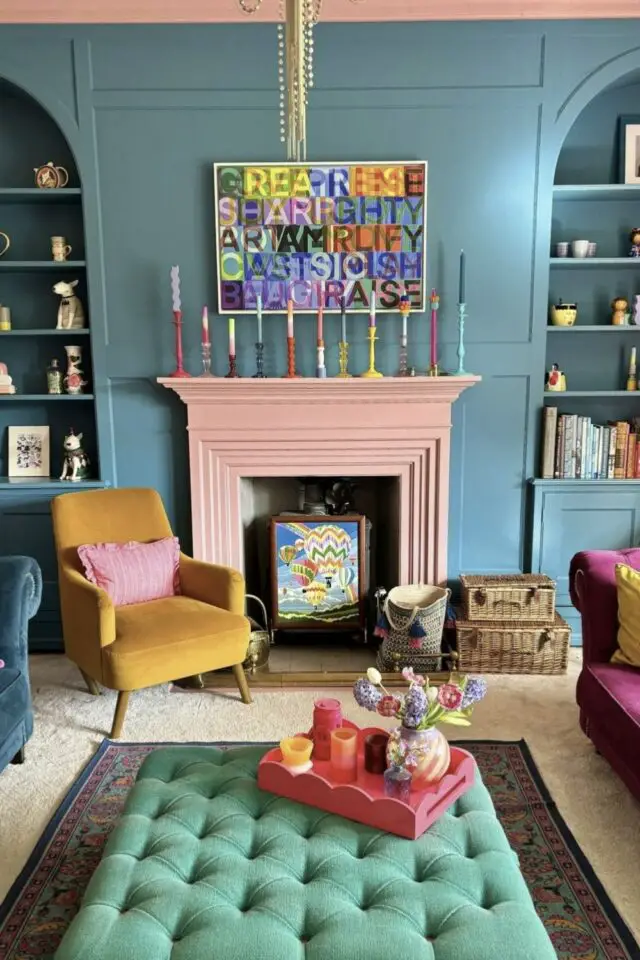 jolie décoration de salon mur bleu cheminée rose point focal bougeoirs tableau fauteuils et canapés colorés pouf table basse capitonnée chic 