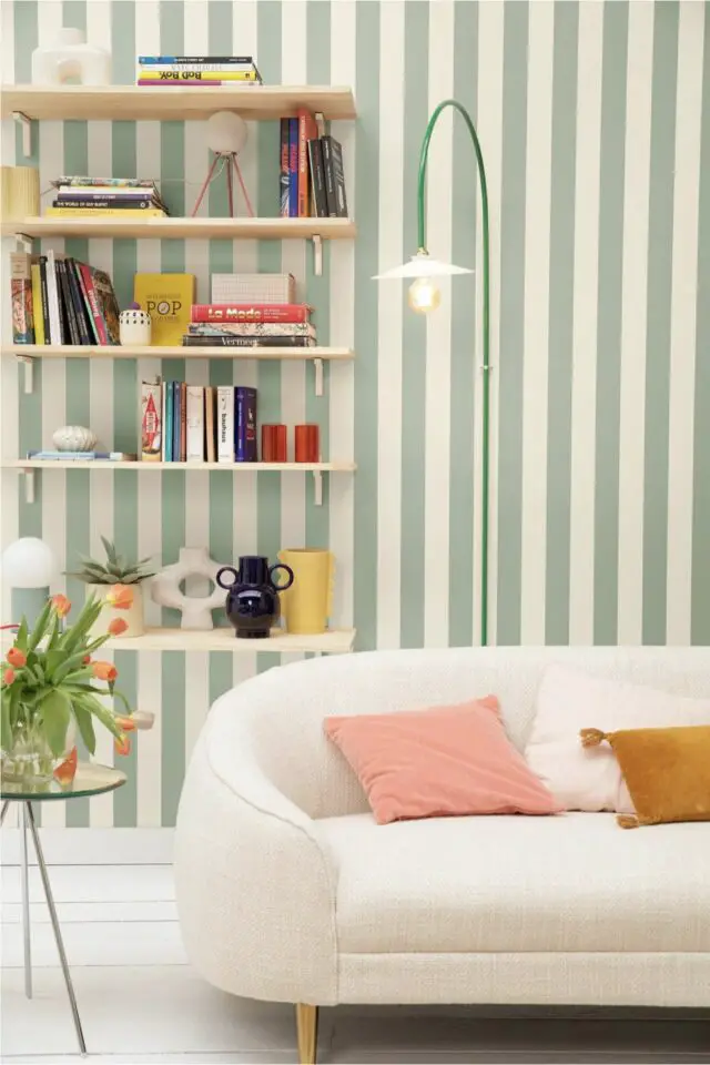 déco de salon meubles blancs canapé neutre moderne étagères murales papier peint rayures vert sauge et blanc pièce à vivre moderne 