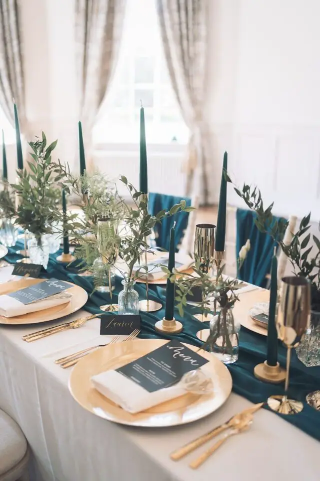 exemple mariage déco bleu sarcelle chemin de table sombre assiette dorée bougies et feuillage eucalyptus élégant 