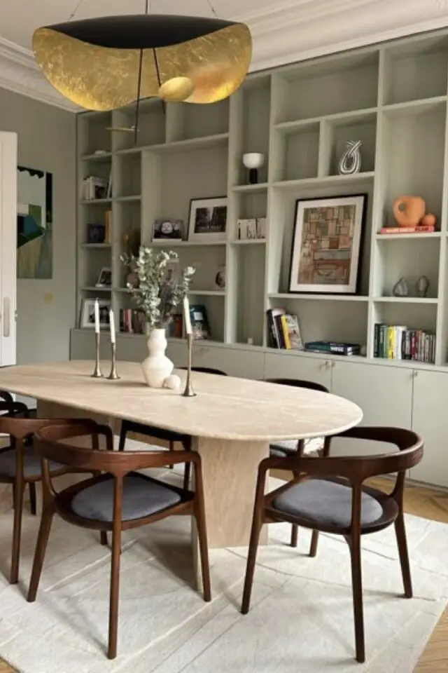tendances déco 2026 salle à manger polyvalente bibliothèque sur-mesure chic table en travertin ovale fauteuil en bois dossier enveloppant tendances déco 2026 salle à manger polyvalente bibliothèque sur-mesure chic table en travertin ovale fauteuil en bois dossier enveloppant