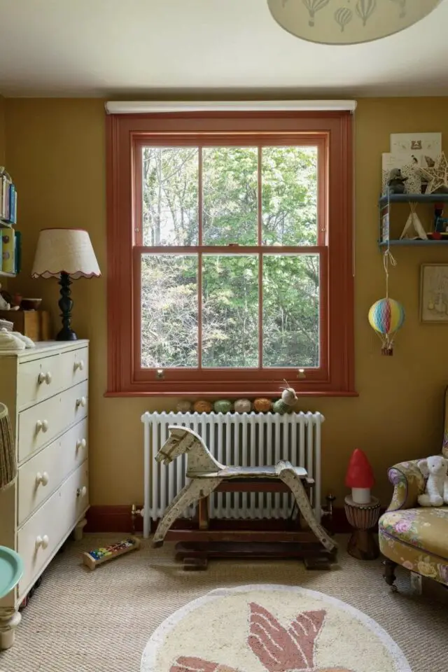 chambre bébé déco vintage jouet ancien cheval à bascule commode en bois mur jaune ocre et fenêtre orange 