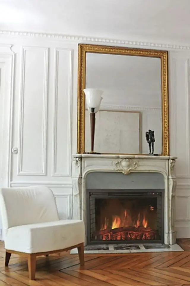 cheminée électrique appartement haussmannien manteau en marbre élégant grand miroir doré ambiance classique moderne  