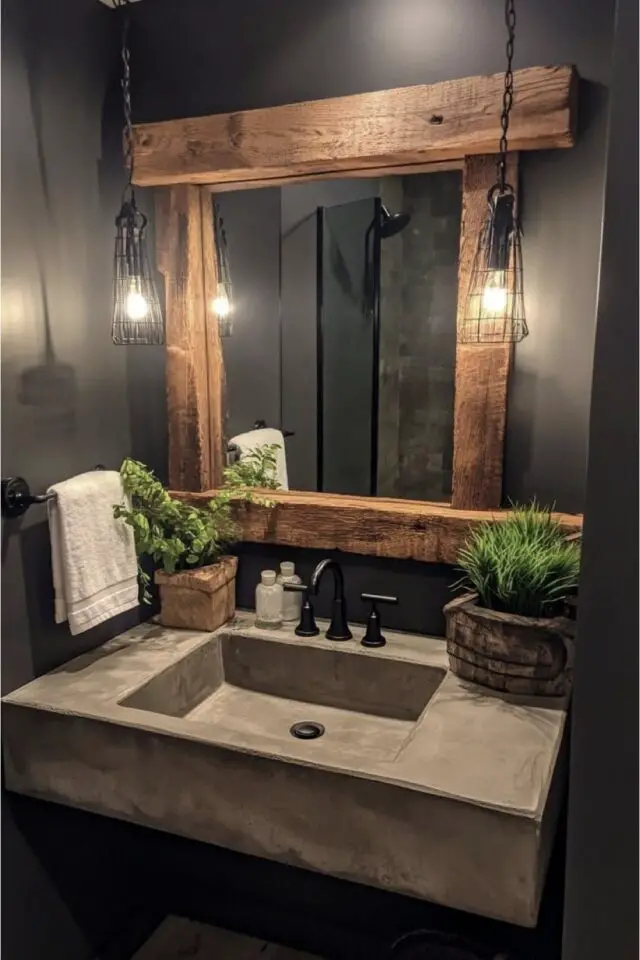 salle de bain déco rustique chic vasque en béton miroir encadrement bois massif plantes vertes et suspension en métal noir 
