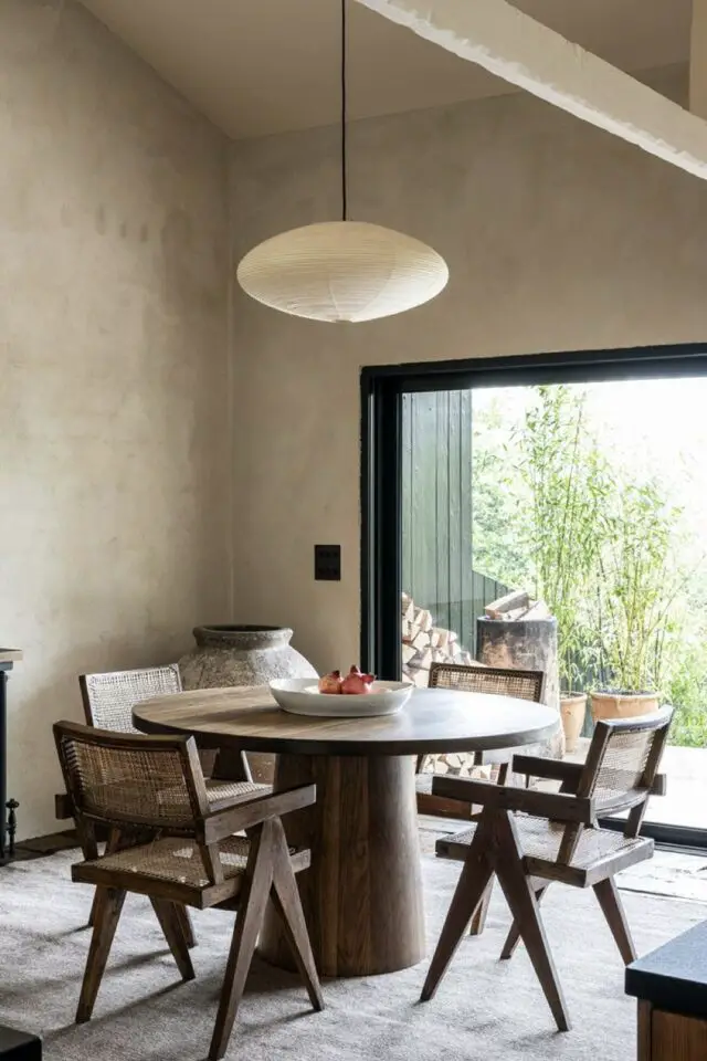 décoration salle à manger style wabi sabi murs revêtement texturé petite table ronde moderne en bois chaleureux fauteuil design cannage 