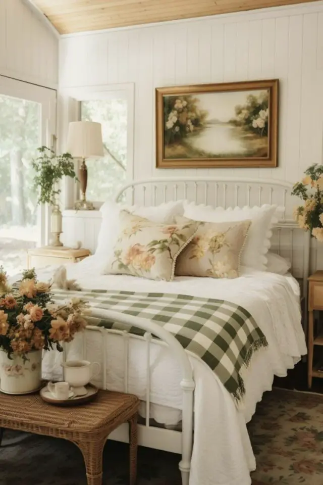 chambre campagne chic lambris blanc lit en métal blanc boutis à carreaux coussins décoratifs motif floral bouqet de fleur tableau paysage 