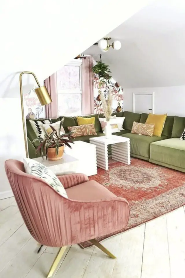 salon mansardé style modern glam mur blanc grand canapé d'angle vert en velours fauteuil vieux rose et lampe dorée 