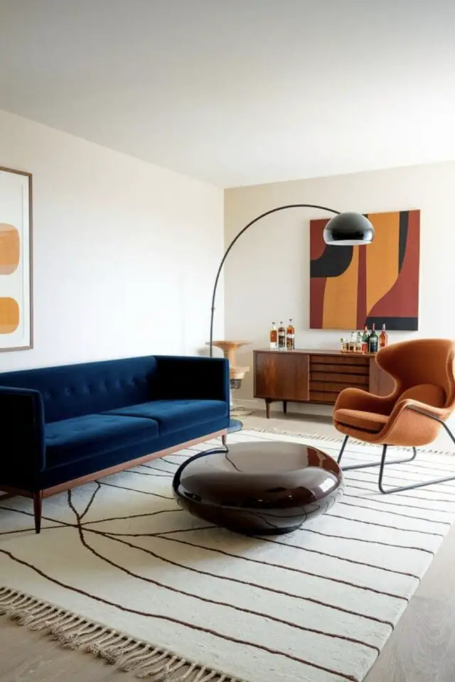 Salon épuré et chic artistique oeuvre d'art au dessus du buffet mobilier mid century modern canapé bleu en velours et fauteuil table basse design 