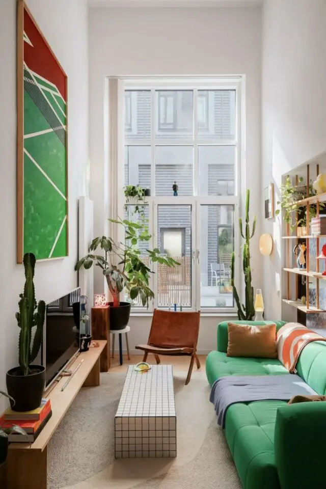petit salon tout en longueur intérieur design canapé vert fauteuil lounge tableau XXL au dessus du meuble TV 