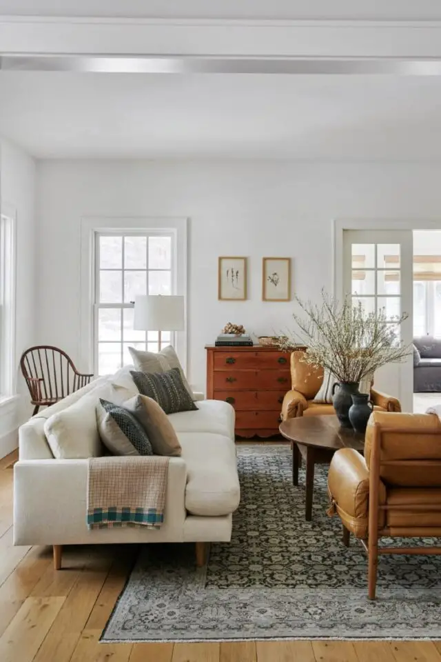 salon meuble en bois rustique ancien petit buffet table basse ronde en noyer canapé blanc fauteuil cuir armature bois tapis gris mur blanc espace lumineux 