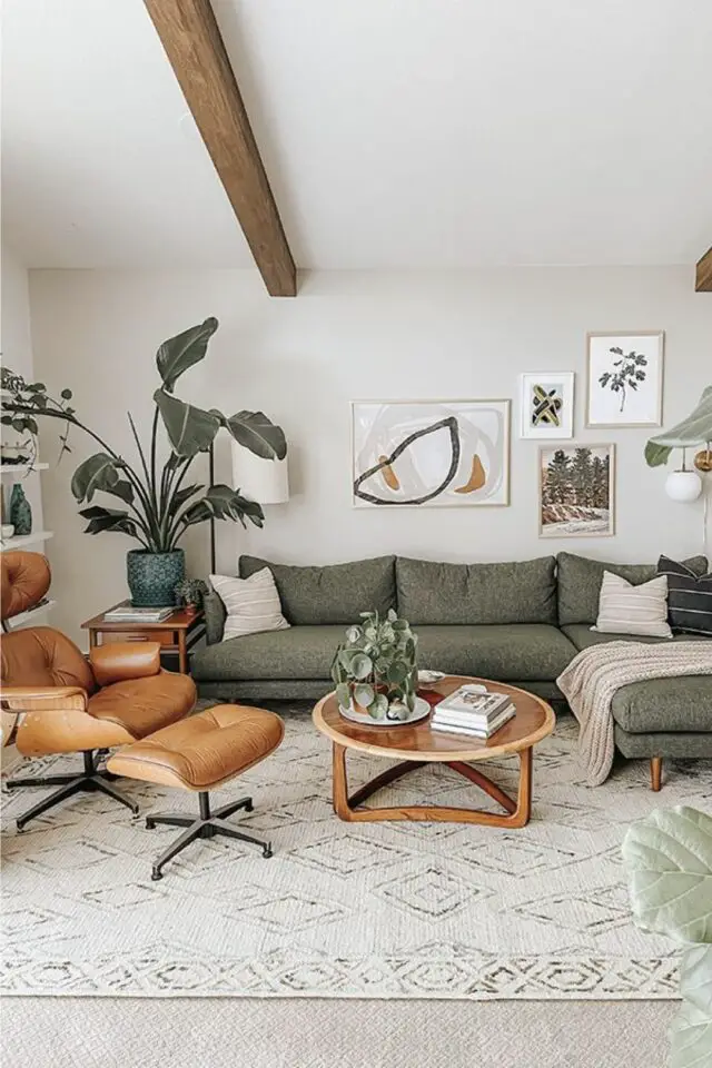 salon mobilier en bois table basse ronde vintage piètement organique grand canapé d'angle fauteuil Eames en cuir mur blanc poutre plafond grande plante verte 