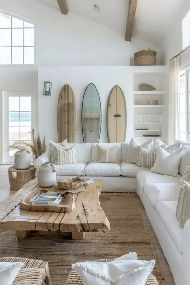 salon style bord de mer grand canapé d'angle blanc coussin écru tapis naturel table basse bois planches de surf en guise de déco murale 