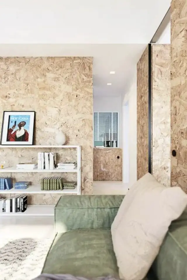 mur en OSB salon moderne canapé vert bibliothèque basse blanche plafond blanc pièce à vivre lumineuse et chaleureuse 
