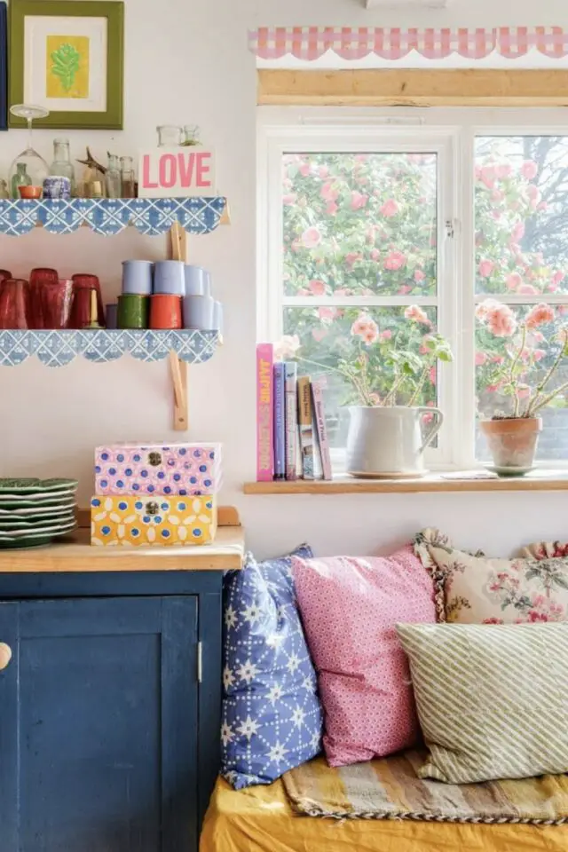 coin banquette cuisine ambiance whimsical mélange de motifs et de couleurs pastel coussins store de fenêtre plantes en pot 