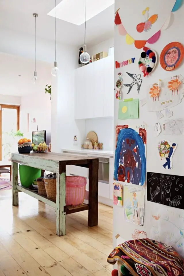 déco cuisine blanche chaleureuse et conviviale îlot central indépendant ancien établi avec peinture patinée dessins d'enfants accrochés au mur 