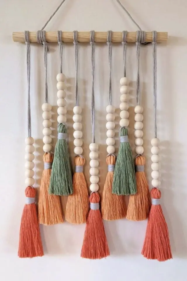 décoration murale bohème avec perles en bois et pompons colorés orange corail et vert sauge idée déco créative activité manuelle adulte 