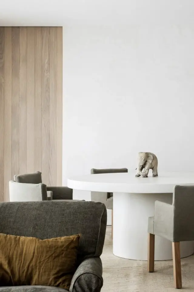 table ronde blanche salle à manger fauteuil gris mur en bois espace ouvert sur le salon ambiance épurée 