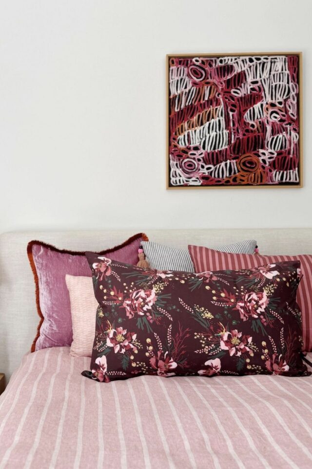 chambre adulte mur blanc avec tableau au dessus du luit à dominante bordeaux housse de couette rayée rose coussin à fleur burgundy 