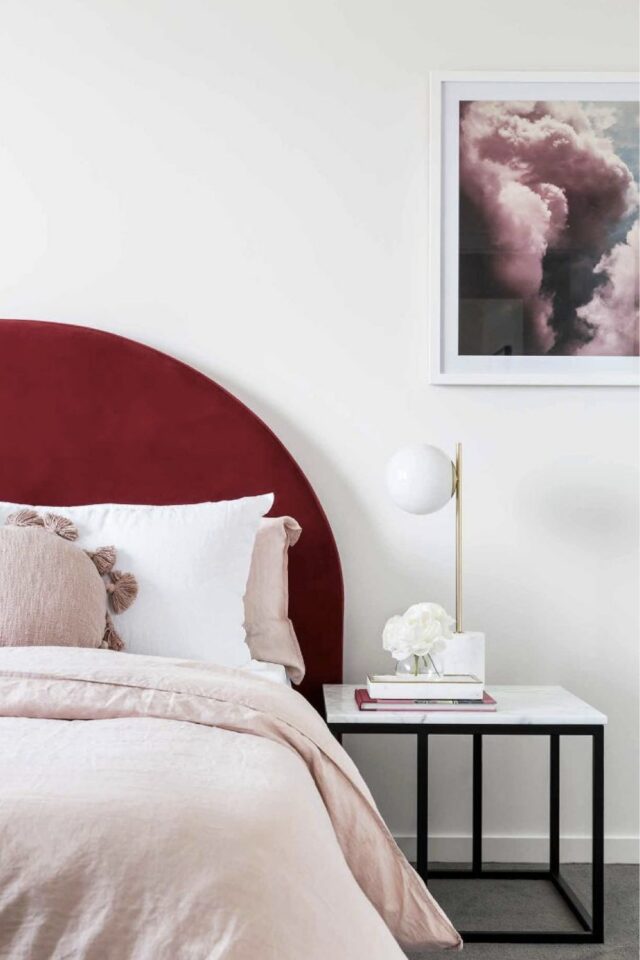 chambre à coucher blanche avec tête de lit arrondie burgundy et housse de couette rose poudré lampe de chevet dorée et opaline 