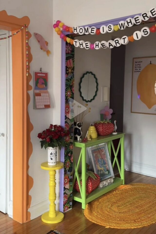 petite entrée à dominante blanche encadrement de porte coloré violet et orange console verte et petit guéridon jaune 