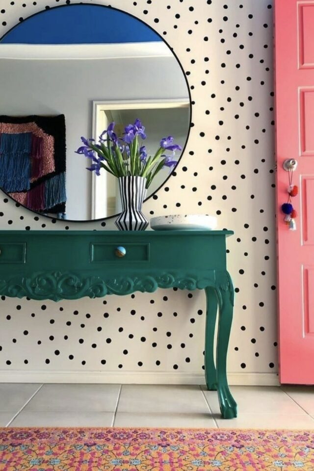 petite entrée claire papier peint blanc à pois noir console verte porte rose et grand miroir rond 