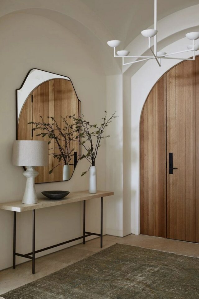 entrée blanche et lumineuse grand miroir mural accroché au dessus d'une console simple lustre blanc et lampe à poser 