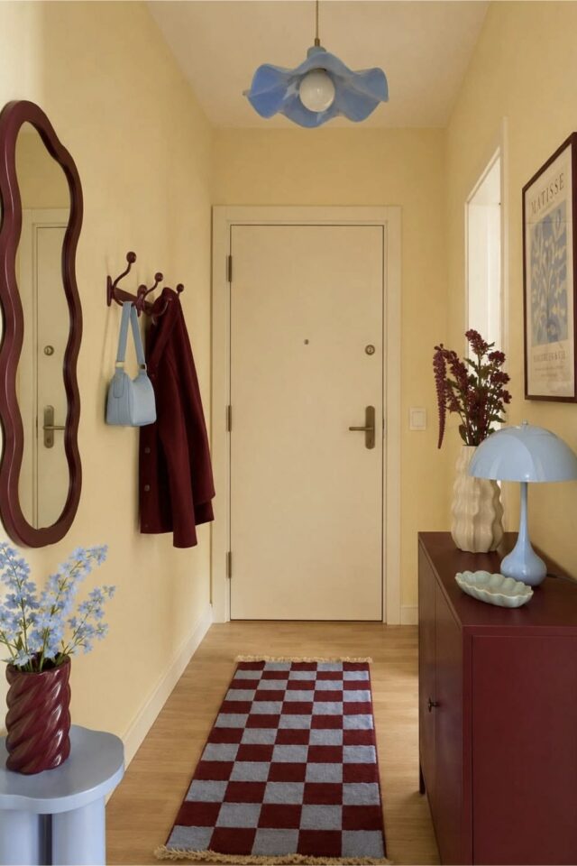 petite entrée d'appartement moderne peinture jaune beurre lumineux meuble et accessoire bordeaux couleur accent bleu ciel 